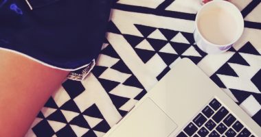 女性の脚とパソコン。副業中